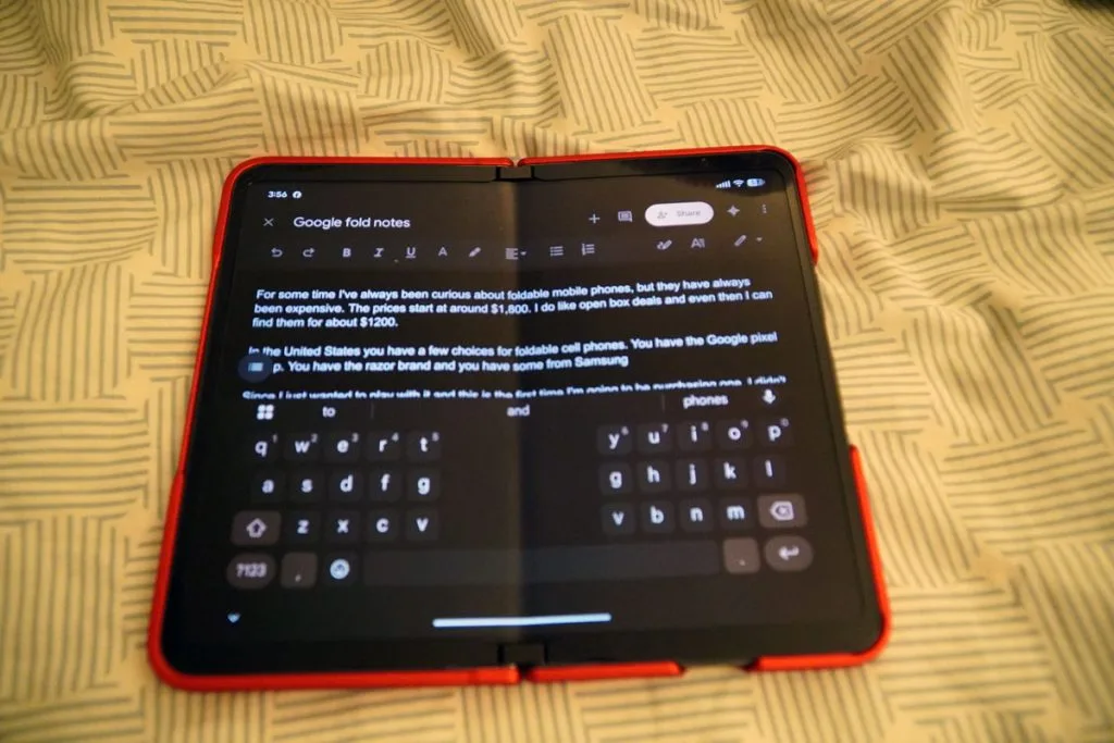 Google Pixel Fold unfolded in red case displaying Google Notes app with split keyboard.
